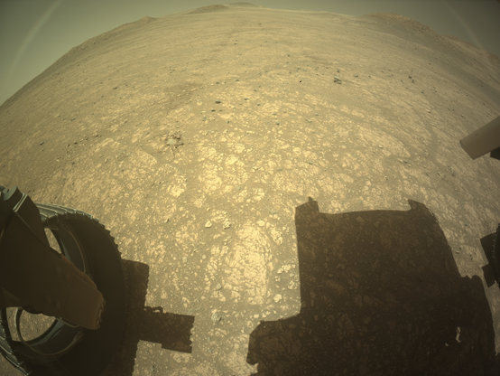 An ochre toned imageof a Martian landscape, captured by the rover's rear hazard avoidance camera.