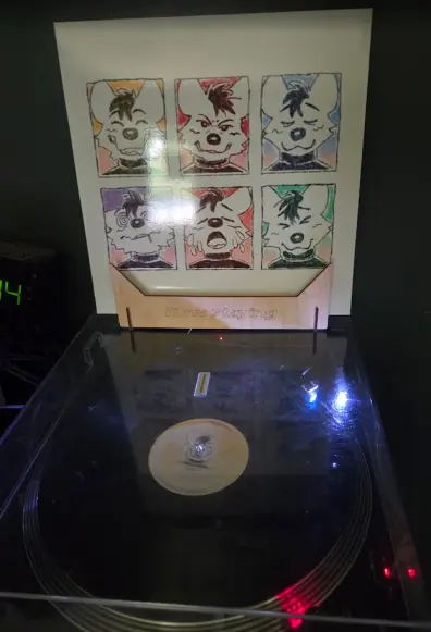 a black vinyl spinnning with the cover above it featuring multiple different expressions from an anthro hyena