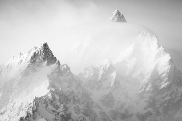 A close-up of the Cathedral Range of the Tetons, seen partially shrouded in clouds in morning light from the Willow Flats Turnout.