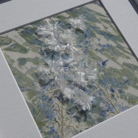 Close up of a mixed media artwork (gel print with stitch embellishment) depicting Rose Bay Willow Herb with its fluffy seeds. The slightly abstract background is blues and khaki colours.