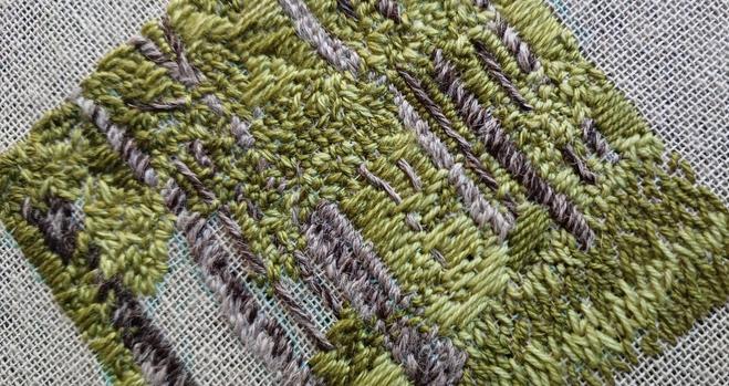 An almost finished stitched artwork depicting a woodland in summer. Lots of different greens! Viewed on an angle to show texture