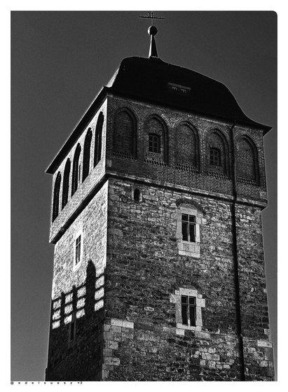 Schwarzweißfotografie: freistehender Turm in der Innenstadt, erbaut Ende 12. Jahrhundert, einst Teil der Stadtbefestigung, gemauert aus namensgebenden rotfarbigen Steinen (Porphyrtuff)