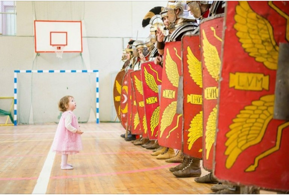 A small child stands before a line of roman legionnaires.