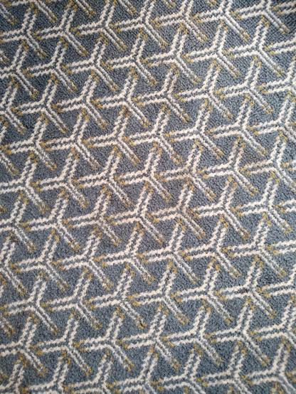 A patterned carpet that looks like two interwoven hexagonal lattices.