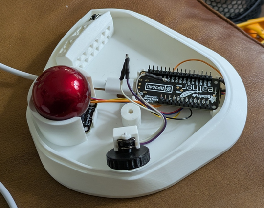 the bottom half of a 3D-printed trackball controller with the trackball, microcontroller, scroll wheel and one button installed