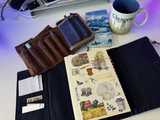 A couple of items are pictured: my pen roll with 5 pens, my Hobonichi Cousin and Weeks and a cup of coffee