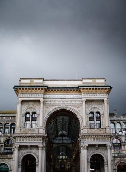 Dark clouds loom above the main arch gate to Galleria Vittorio Emanuele II.