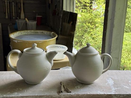 a photo of two wheel thrown porcelain teapots. They are unfired and ready for decoration.