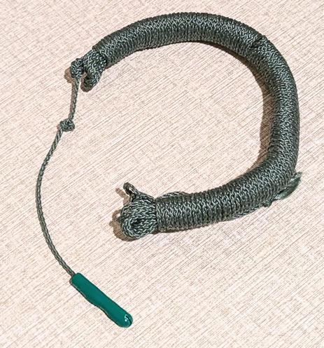A green bracelet made from wound up kevlar cord with a green aglet to help thread a stopper knot through a loop to secure on the wrist.