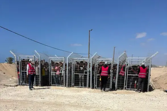 Palestinians behind gates before entering a food distribution site operated by the Gaza 'Humanitarian' Foundation [AP]