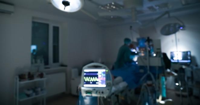Unscharfe Ansicht von Ärzt:innen, die einen Patienten nachts im Operationssaal operieren.