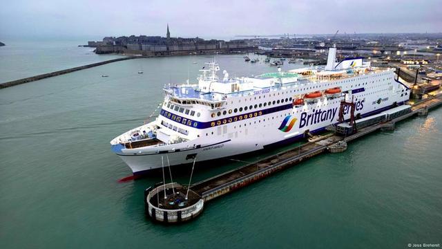 Drohnenaufnahme eines Schiffes mit der Stadt St.Malo im Hintergrund. Die Hybridfähre pendelt zwischen Frankreich und GB auf einer Strecke von bis zu 260 Kilometer und kann durch den Antrieb mit Strom aus Batterien den CO2-Ausstoß während der Überfahrt um 25% senken.  