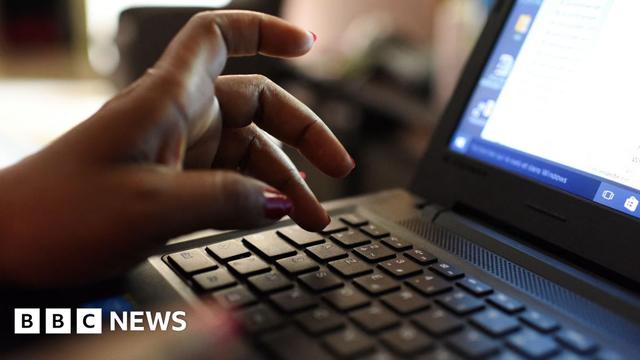A close-up photo of a woman's hand using a laptop.