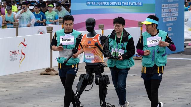 Un robot humanoide llamado Tiangong corre con técnicos de apoyo el 19 de abril de 2025 en Pekín, China. Getty Images / Kevin Frayer
