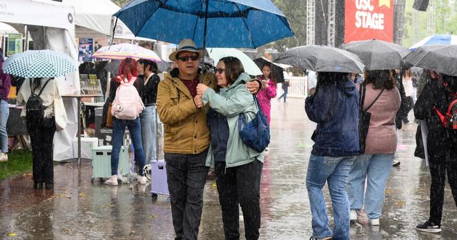 LOS ANGELES, CALIFORNIA - APRIL 26, 2025: Saul Duarte, left, and his wife, Suzanne walk in the rain during the Los Angeles Times Festival of Books at USC on Saturday, April 26, 2025, in Los Angeles. (William Liang / For the Times)
