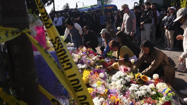 Des personnes déposent des fleurs.