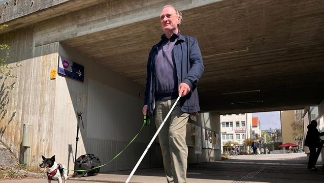 Ein Blinder mit einem Blindenstock und einem Hund in der S-Bahn Unterführung 