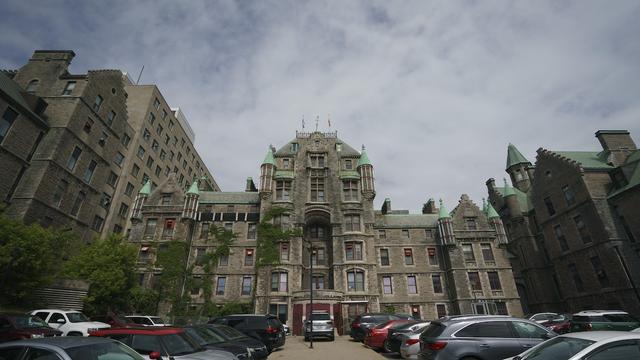 L'entrée de l'ancien hôpital, tandis qu'on voit des voitures stationnées devant.
