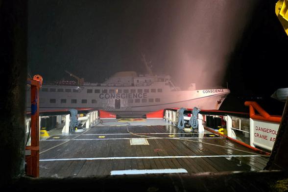 Ein Schiff undeutlich in der Dunkelheit. Rauchschwaden schweben in der Luft