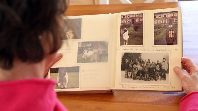 Eine Frau blickt in ein Fotoalbum mit Aufnahmen aus dem Jahr 1971