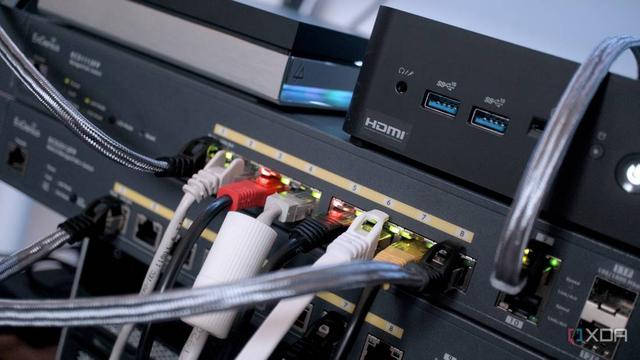 Close-up of network devices and cables, showcasing a gaming console, HDMI ports, and lit indicators on a patch panel.