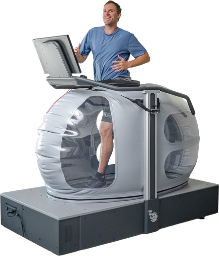A man runs on a high-tech treadmill. Attached to the treadmill is a large bubble-like structure surrounding his lower body.