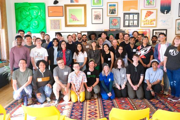 A group of people smiling at the camera in front of a gallery wall