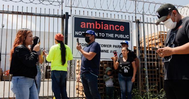 A crowd formed at the back gate of Ambiance Apparel in Los Angeles on Friday after federal immigration agents gathered at the company.