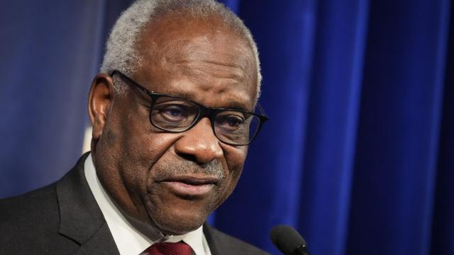 Supreme Court Justice Clarence Thomas speaking into a microphone at an event.