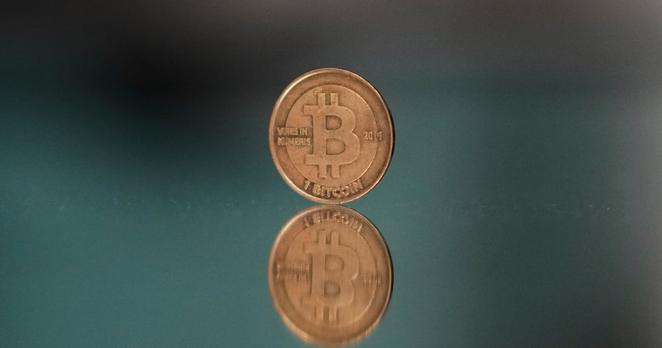 FILE - A bitcoin token is placed on a mirror for a photograph in Prague, Czech Republic, Sunday, May 11, 2025. (AP Photo/Petr David Josek, File)
