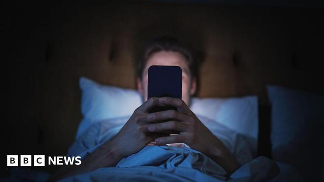 A man looking at his phone in bed