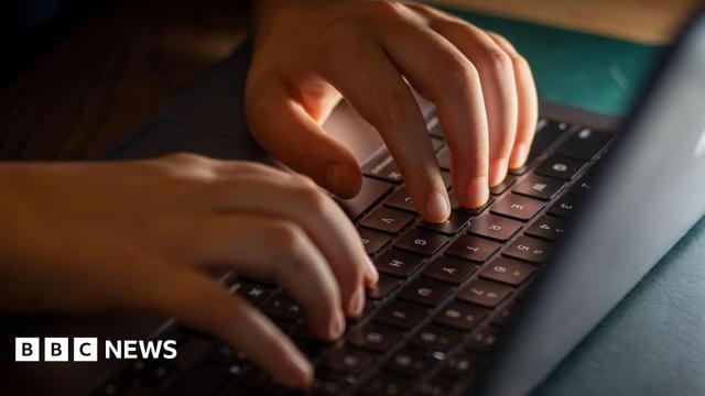 A child's hands type on a computer.