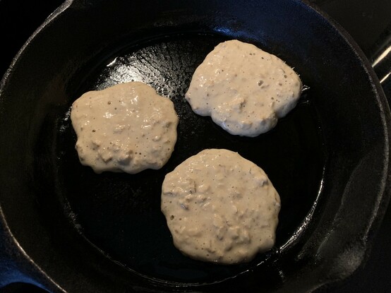 Oatmeal pancakes sizzling in a cast iron skillet