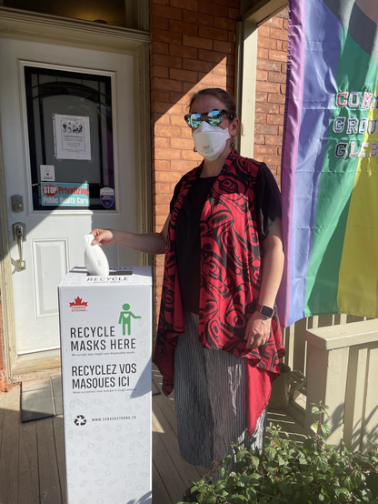 Photo of me putting a mask into a Canada Strong recycling box