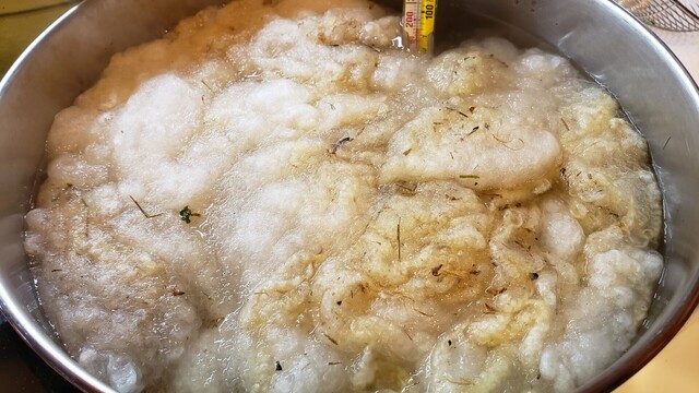 Wool in a mordant bath with a thermometer reading around 180°F.
