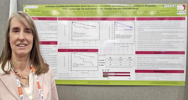 Foto of a woman in front of the conference poster.