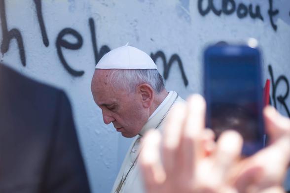 Pope Francis backs up slowly with his head bowed after praying at the military gate in the Israeli built Apartheid Wall in the West Bank city of Bethlehem on May 25, 2014. (Photo: Kelly Lynn)