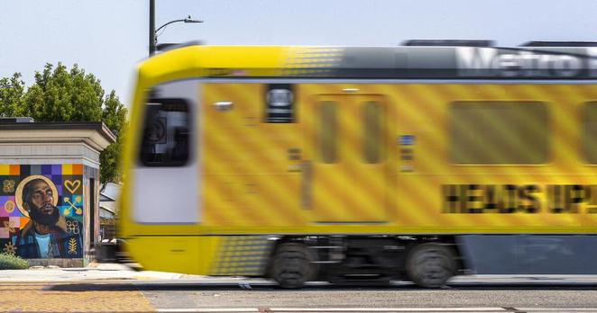 LOS ANGELES, CA -AUGUST 22, 2022:A metro train, traveling on the new K Line, goes past a mural of the late rapper Nipsey Hussle, located on Crenshaw Blvd.at Slauson Ave. in Los Angeles, during a test run. Metro's K Line (Crenshaw/LAX Transit Project) will extend light rail from the existing Metro E Line (Expo) at Crenshaw and Exposition Boulevards to the Metro C Line. While the rail line includes 8 new stations, only 7 will be open in the fall of 2022. The train will travel 8.5 miles and will serve the cities of Los Angeles, Inglewood, and El Segundo and portions of unincorporated Los Angeles County. (Mel Melcon / Los Angeles Times)