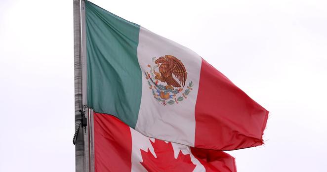 The flags of Mexico and Canada fly near the Ambassador Bridge, Monday, Feb. 3, 2025, in Detroit. (AP Photo/Paul Sancya)
