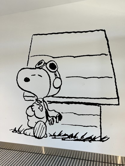 Drawing of Snoopy in his aviator hat and goggles, leaning on his house whilst looking super cool, on a wall at STS