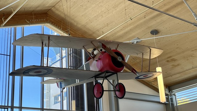 Sculpture of Snoopy flying a vintage plane, hanging in the baggage claim area of STS