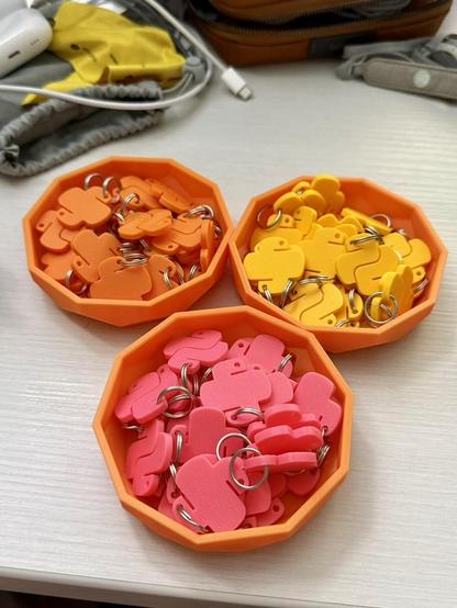 Orange plastic bowls containing keychain charms of the Python logo in orange, yellow, and pink