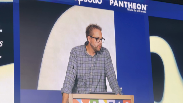 Dries Buytaert on stage but the background of the image looks like heat distortion, like he’s on fire. 