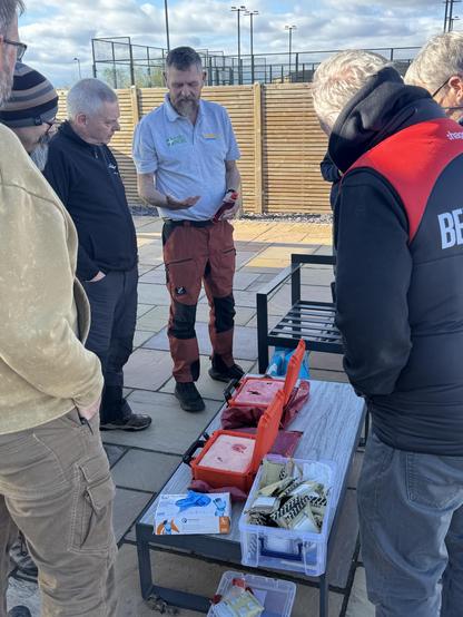 Some people stood over boxes containing false body parts that have deep wounds oozing blood that we were practicing packing. 