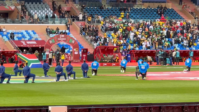 Players coming out onto the pitch at start of play. Crowds behind. 