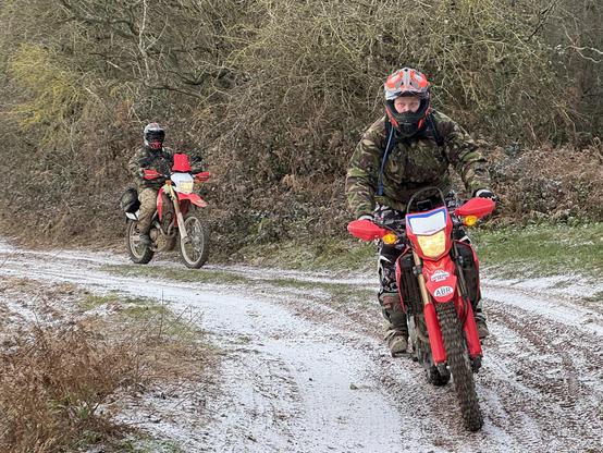 Two women riding motorcycles on a snow-covered dirt track