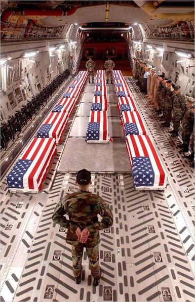 Coffins of dead soldiers in the back of a military transport plane, each covered in a USA flag. 