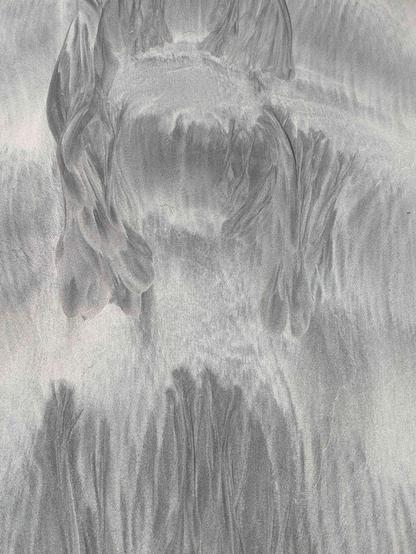 a pattern in silver and grey sand. just maybe there's something that looks like the head and shoulders of a person in this.