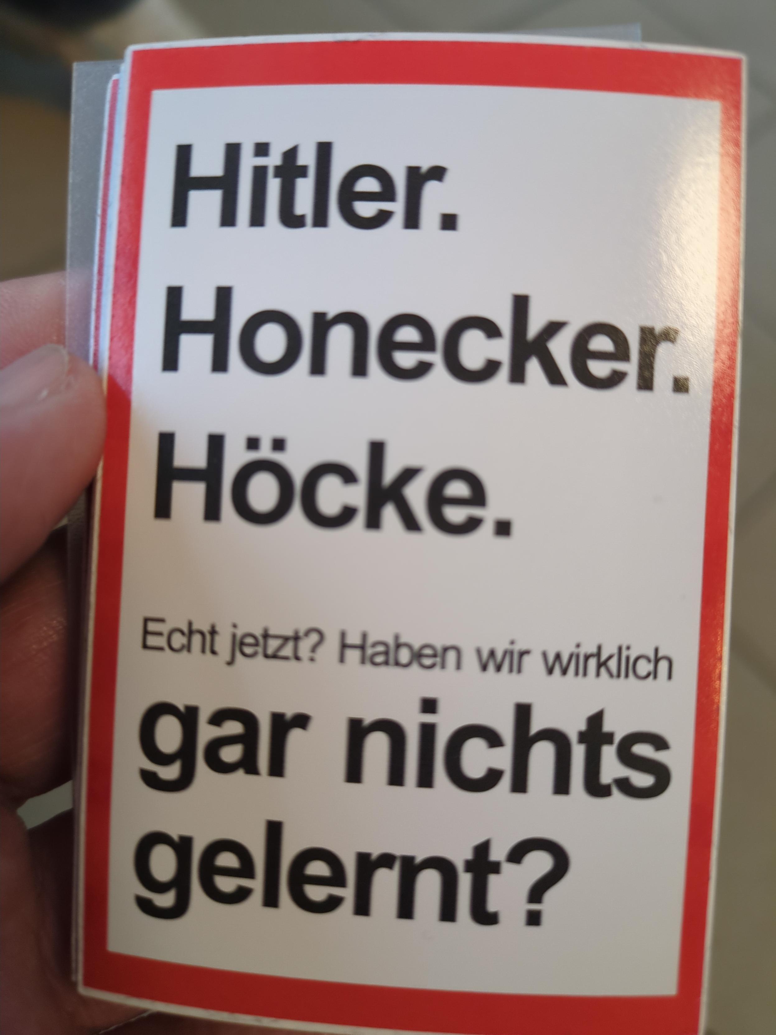 Weißer Sticker, rechteckig hochkant, mit rotem Rahmen und schwarzem Text: "Hitler. Honecker. Höcke. Echt jetzt? Haben wir wirklich gar nichts gelernt?"