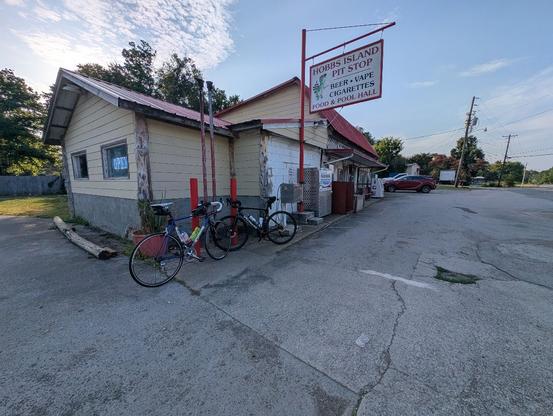 Two road bicycles leaning against red posts next to a rural gas station, the Hobbs Island Pit Stop.